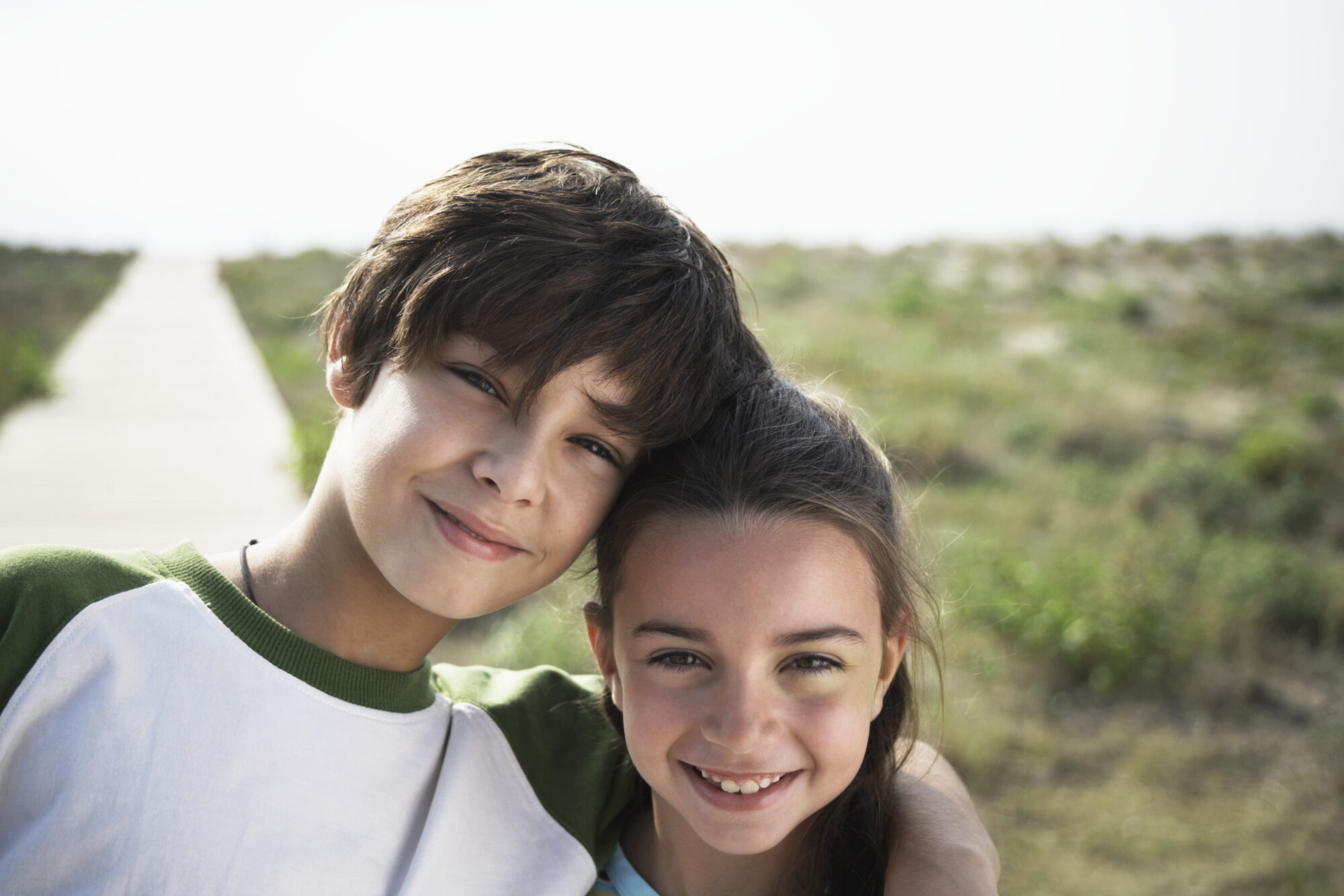 Boy and girl (8-10) on beach boardwalk, close-up, portrait Pediatric Dentist