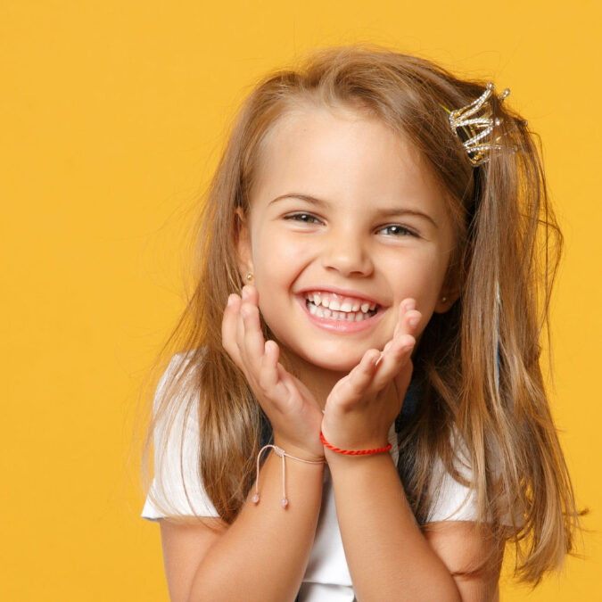 Little cute child kid baby girl 4-5 years old wearing light denim clothes isolated on pastel yellow wall background, children studio portrait. Mother's Day, love family, parenthood childhood concept