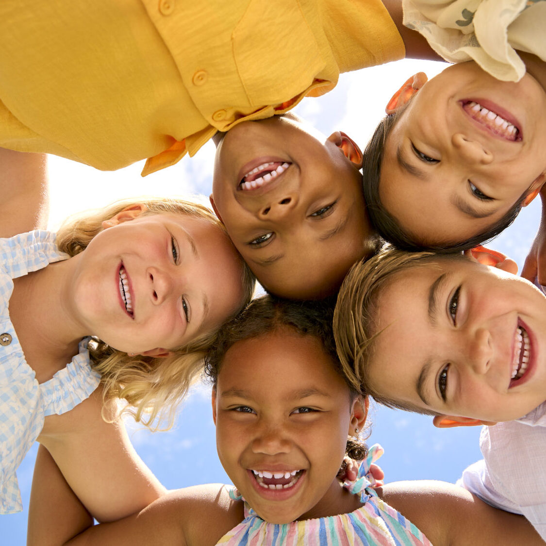 Group Of Multi-Cultural Children Friends Linking Arms Looking Down Into Camera Our Practice