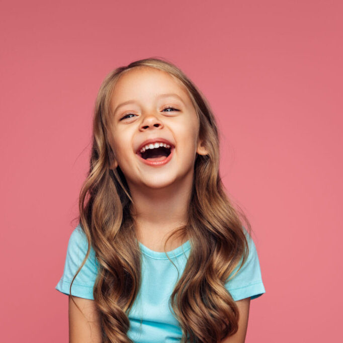 Smiling girl on a pink background, calm and happy after IV sedation pediatric dentistry in Sugar Land, TX