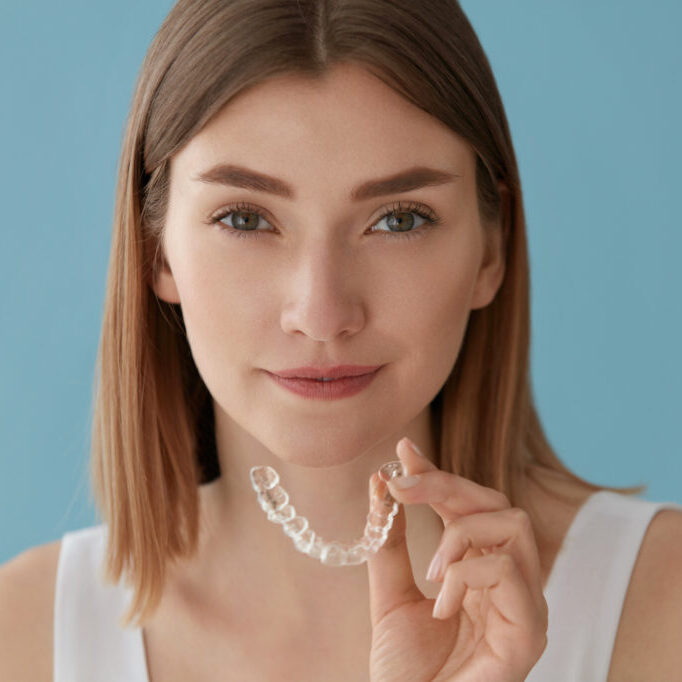 Patient holding a clear aligner – orthodontics Sugar Land, TX families trust at Healthy Teeth Pediatric Dentistry